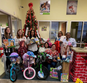 staff holding gifts in front of the angel tree