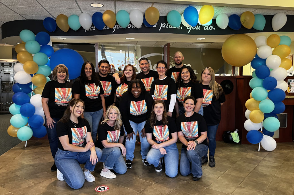 staff posing in front of member appreciation day balloon display