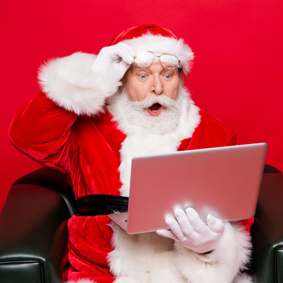 man dressed as santa looking at computer with a shocked expression