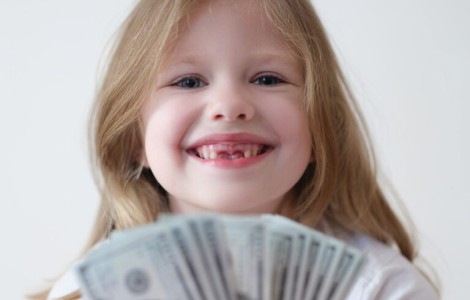 little girl smiling while holding handful of $100 bills