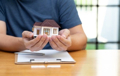 man holding minature house in his hands