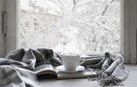 coffee on table next to window with beautiful snowfall outside