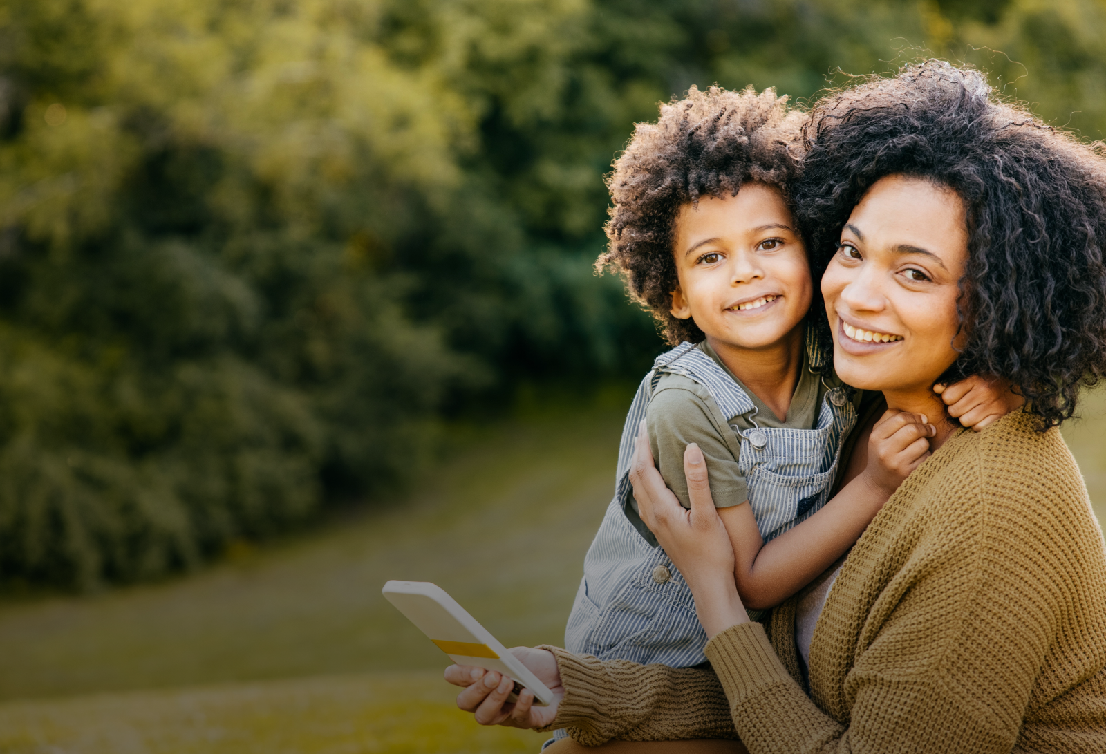 mother holding her young child outdoors, both looking at camera