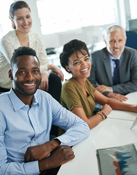 4 colleagues in a casual office environment looking at the camera and smiling