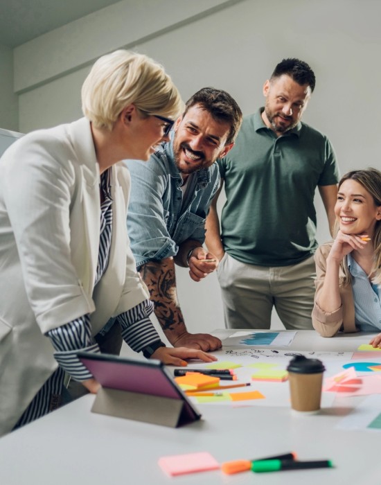 4 team members smiling while collaborating in casual office environment